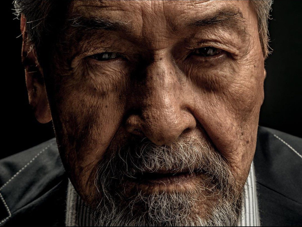 A dramatic, low-key editorial close-up portrait of actor Eddie Garcia in a pinstriped suit against a dark background, from a feature in Esquire Philippines.
