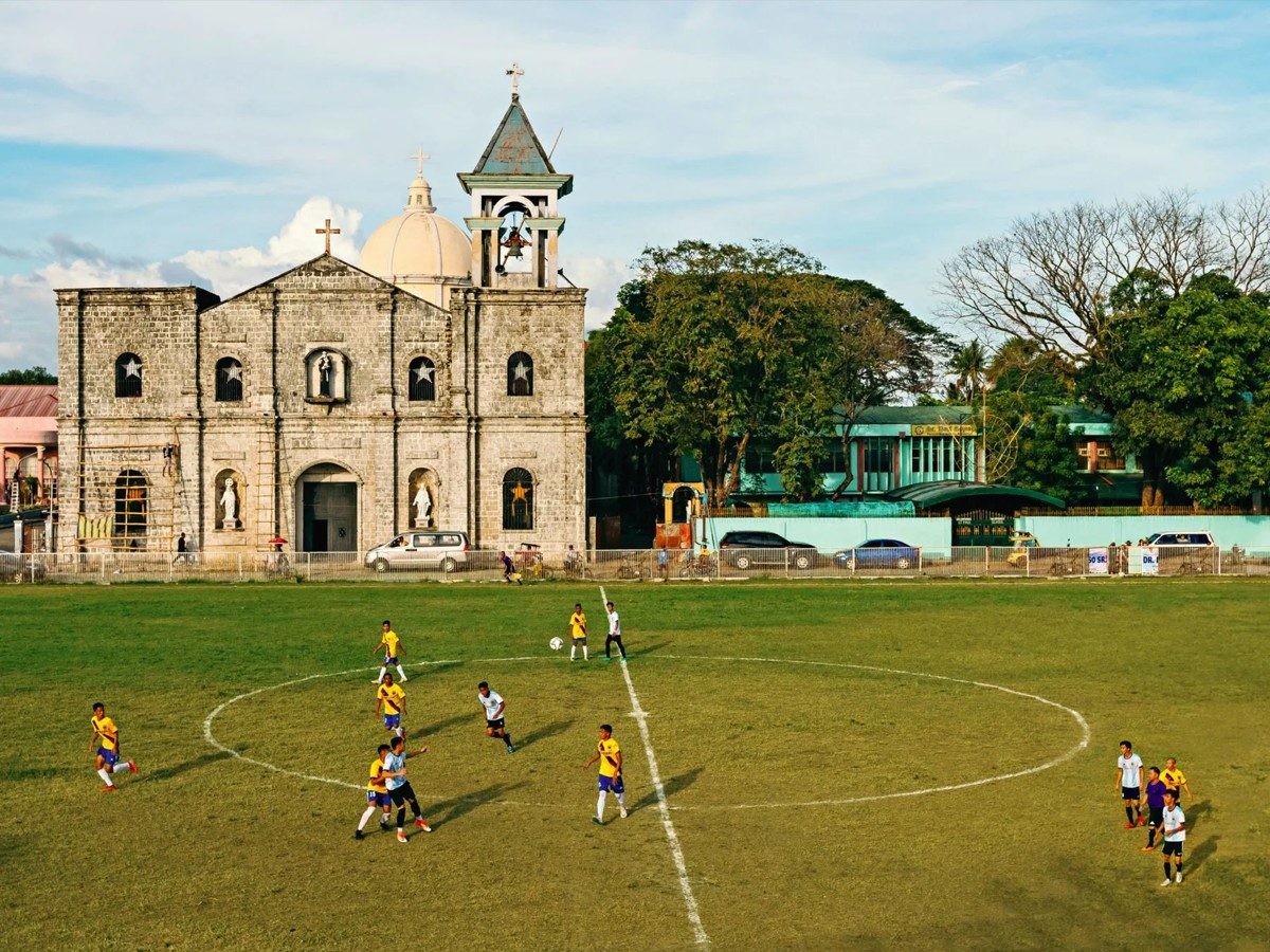 A football match on the town plaza pitch in front of the historic Barotac Nuevo church in Iloilo, for the Smile magazine cover story.