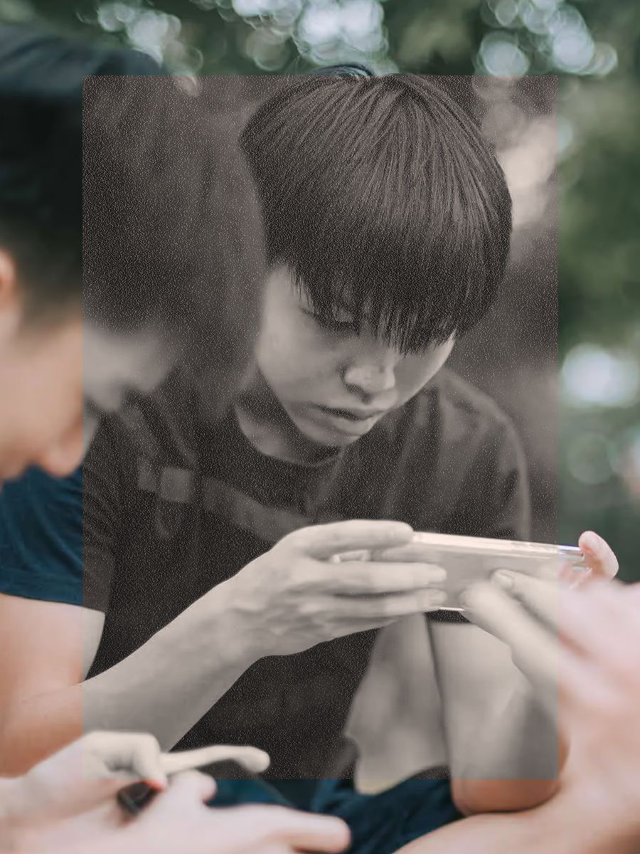 A young person absorbed in a phone screen — from the launch of Singapore’s Online Safety Commission.